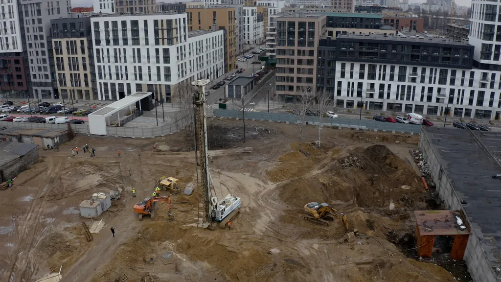 Piling rig at work on a site beside a finished residential development