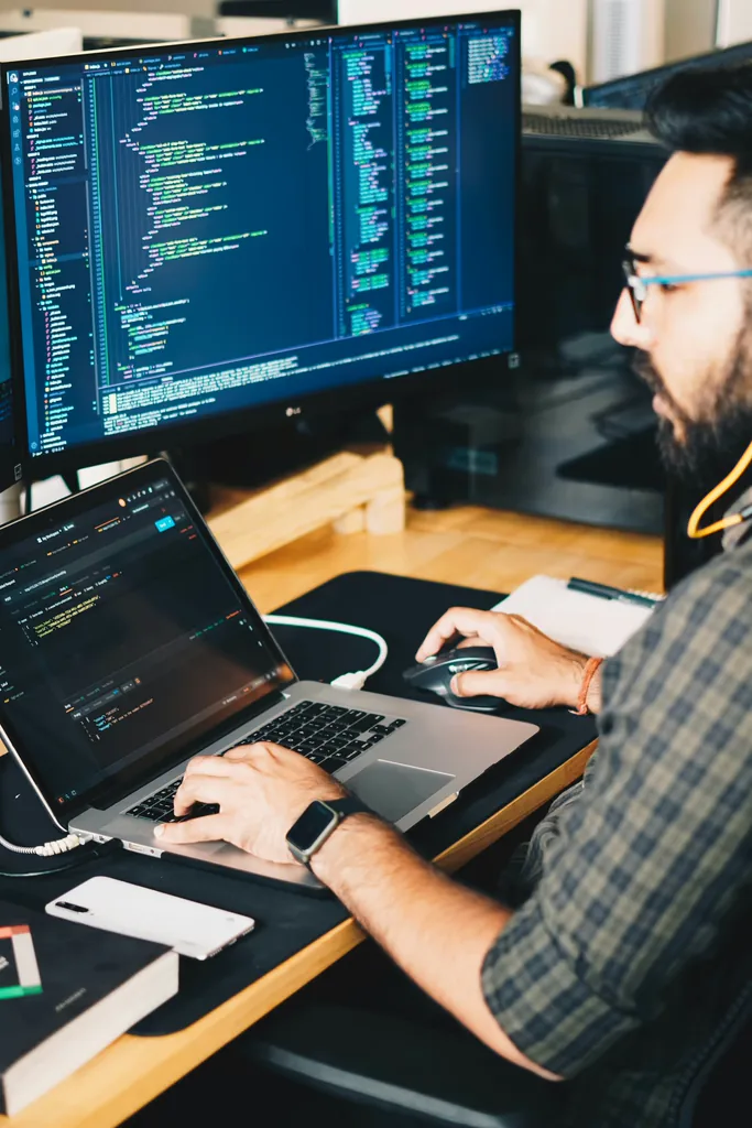 Developer at a desk with plugin code open across two screens