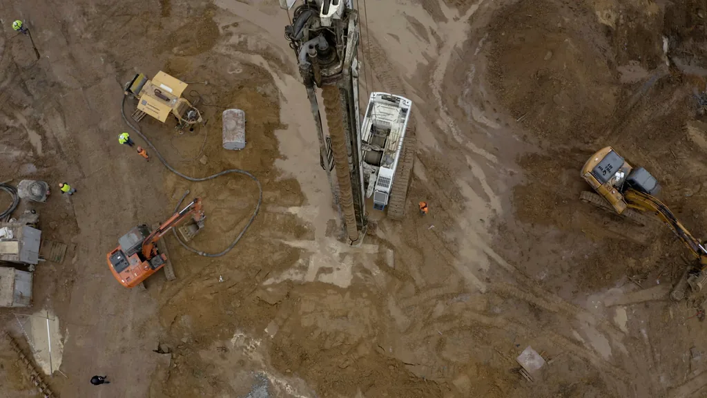 Aerial view of an excavation with a drilling rig and excavators at work